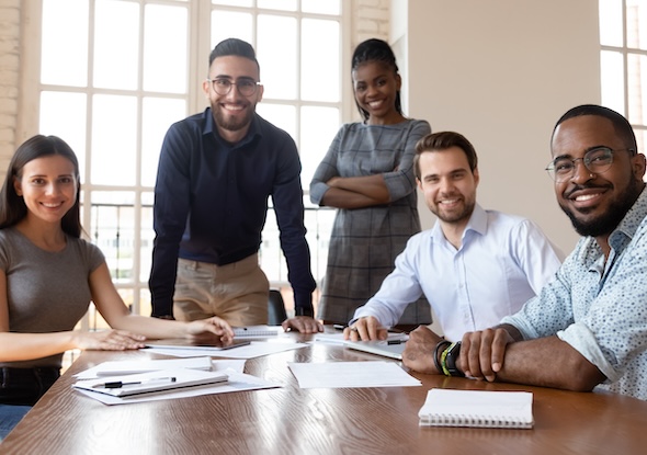 Happy successful multiracial business team gathered in modern boardroom for brainstorming working together on project posing look at camera teamwork representative of smart skilled specialists concept